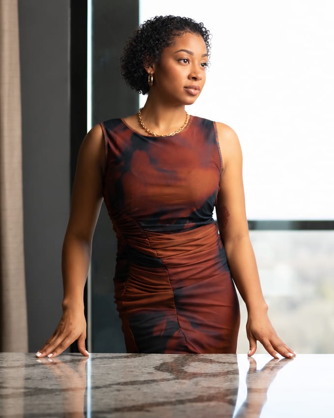 Vania Locklin standing at a marble conference table beside floor-to-ceiling windows
